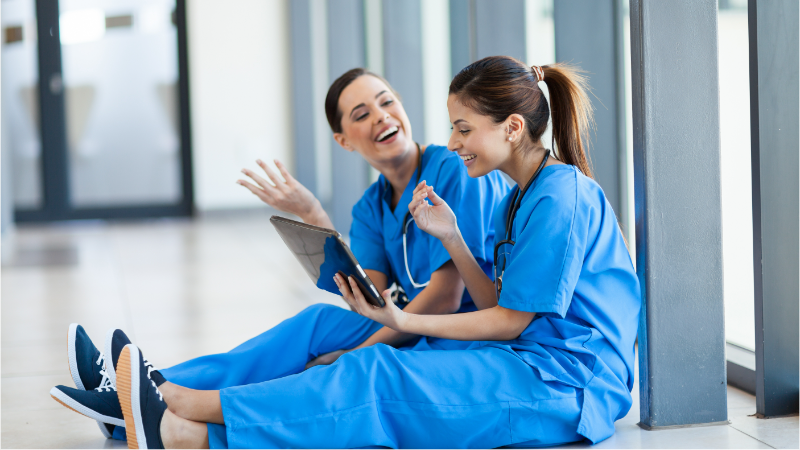 Group of locum tenens APPs sitting and laughing in hallway.